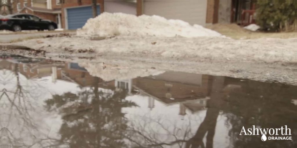 Ashworth drainage logo, spring thaw water in front of house